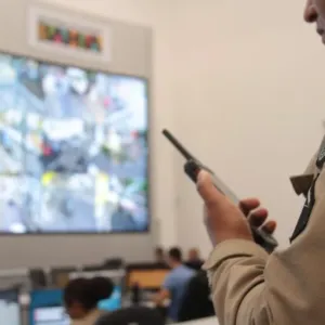 a imagem mostra um policial militar observando câmeras de segurança