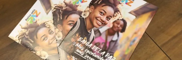 A imagem mostra três livros iguais em uma bancada marrom