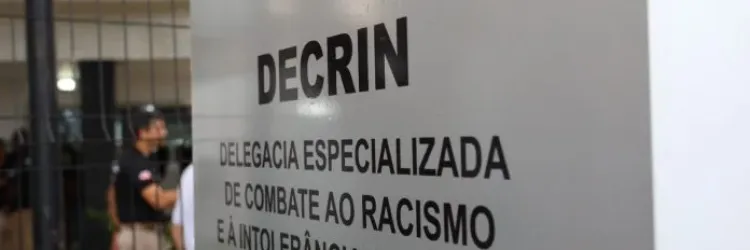 A imagem amostra uma placa escrito "Decrin, delegacia especializada de combate ao racismo e à intolerância religiosa"