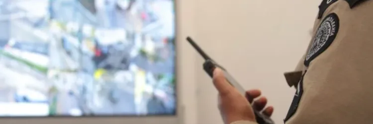 a imagem mostra um policial militar observando câmeras de segurança