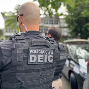 Um policial do DEIC está de costas em primeiro plano