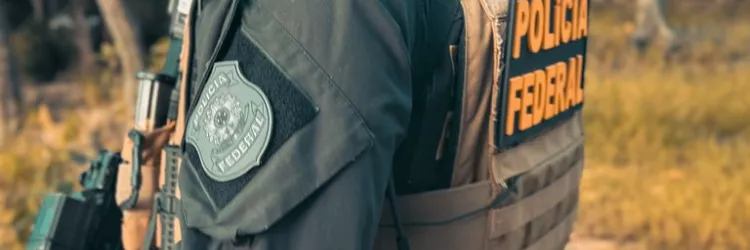 Um policial federal aparece segurando uma arma