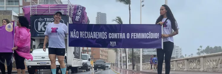 Duas mulheres seguram o cartaz da campanha