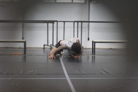 Imagem enquadra uma pessoa inclinada ao chão que usa um colete prateado. Os cabelos cobrem o rosto.