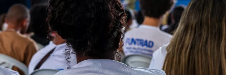 foto de auditório com foco na parte traseira da camisa de uma das pessoas, que está escrito FUNTRAD
